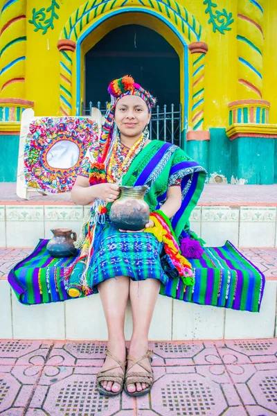 一个女人坐在一座房子的粮仓里摆出一副照片 手里拿着一个壶和漂亮的织物 — 图库照片