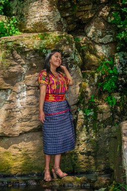 Tipik Maya kostümlü kadın, fotoğrafa poz veriyor, arka planda onu çevreleyen güzel manzara ve doğa.