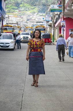Tipik Maya kostümlü genç bayan, fotoğrafa poz veriyor, arka planda sokaktaki güzel manzara.
