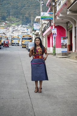 Tipik Maya kostümlü genç bayan, fotoğrafa poz veriyor, arka planda sokaktaki güzel manzara.