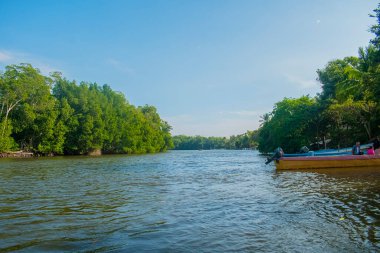 Beautiful summer sunset bluish sky, flared clouds, waves, boats, palm trees around the sea and sand