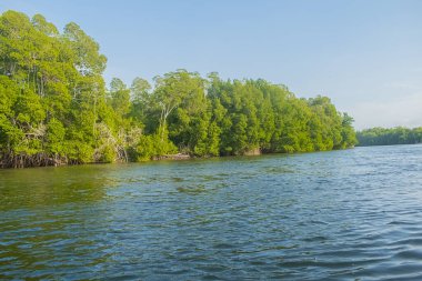 Beautiful summer sunset bluish sky, flared clouds waves boats, trees around sea and sand
