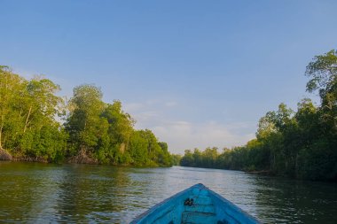 Beautiful summer sunset bluish sky, flared clouds waves boats, trees around sea and sand