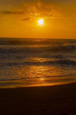 Beautiful summer sunset reddish sky, flared clouds waves, sea and sand