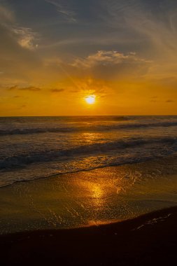 Beautiful summer sunset reddish sky, flared clouds waves, sea and sand