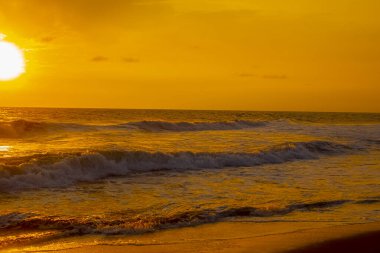 Beautiful sunset orange sky, flared clouds waves, sea and sand