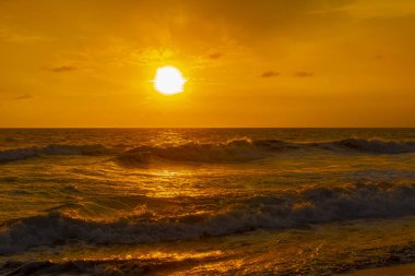 Beautiful sunset orange sky, flared clouds waves, sea and sand