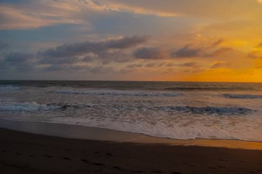 Beautiful sunset reddish sky, flared clouds waves, sea and sand