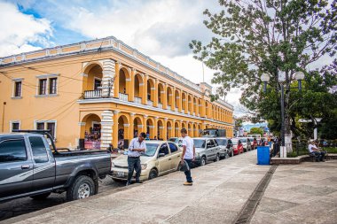 Sarı renkli ve araçlı belediye binası.