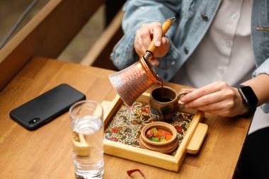 Kadın eli kahve için Türk kahvesi doldurur.
