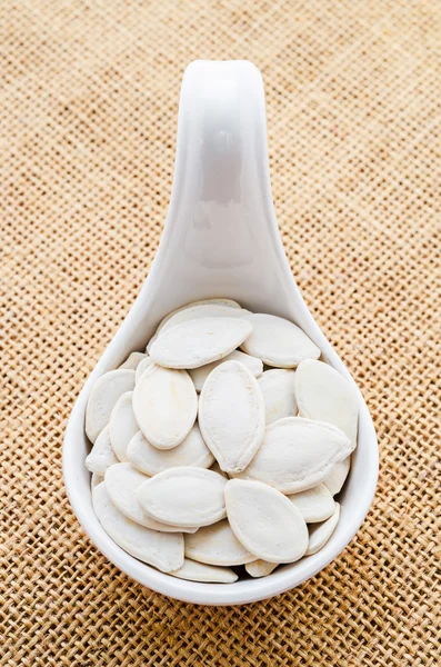 Semillas de calabaza en una cuchara blanca . —  Fotos de Stock