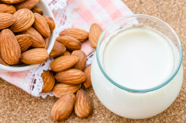 Almond milk in glass with almonds seeds.