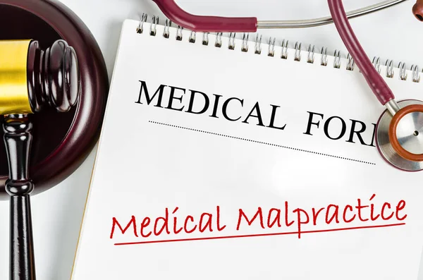 Medical form with words Medical Malpractice and judge\'s hammer gavel and stethoscope medical. Medical malpractice law concept.