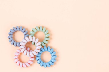 Renkli spiral lastik bantlar. Pembe arka planda canlı renklerde elastik saç bağları.