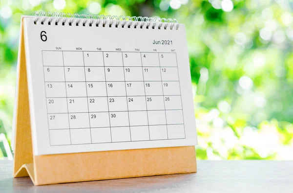 June 2021 Calendar desk for organizer to plan and reminder on wooden table on nature background.