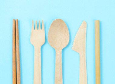 Çevre dostu tek kullanımlık alet konsepti. Mavi arka planda bambu ya da ahşap çatal bıçak takımı.