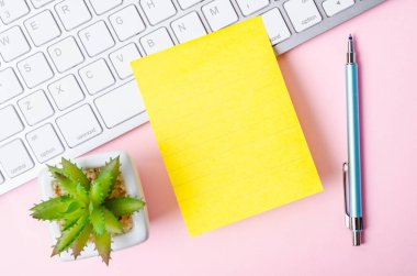 Pembe arkaplandaki mesaj veya metin için klavye bilgisayarına boş sarı yapışkan not.