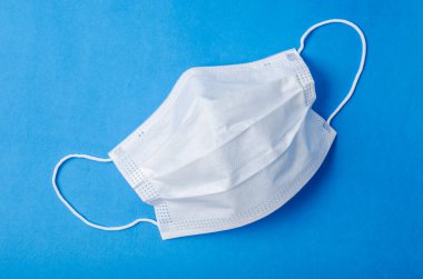 Mavi arka planda tıbbi tek kullanımlık yüz maskesi.