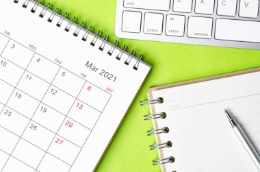 Yeşil arkaplan üzerine not defteriyle Mart 2021 takvimi.