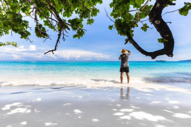 Güzel kumlu sahil ve bir erkek turist Similan Adaları, güzel tropik ada Tayland 'da el sallayarak fotoğraf çekiyorlar..