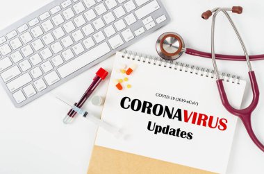 CORONAVIRUS UPDATES ve aşı şişesi. Laboratuvarda test için tüpte kan örneği var. Covid-19 kavramları ve koronavirüs.