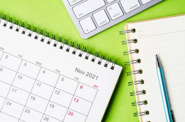 Yeşil arkaplan üzerine not defteriyle Kasım 2021 takvimi.