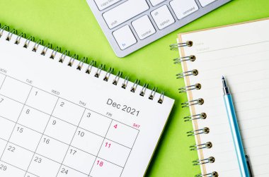 Yeşil arkaplan üzerine not defteriyle Aralık 2021 takvimi.