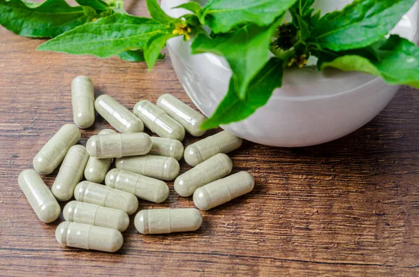 Pile Herbal Medicine Capsules Ceramic Mortar Green Leaf Wooden Background — Stock Photo, Image