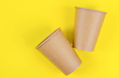 Kahve, çay ve sarı arka planda bulunan çevresel malzemeler için tek kullanımlık kahverengi kağıt bardak..