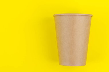 Kahve, çay ve sarı arka planda bulunan çevresel malzemeler için tek kullanımlık kahverengi kağıt bardak..