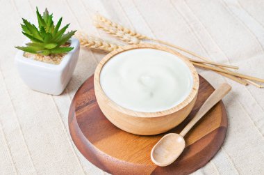 Tahta bir kasede Yunan yoğurdu ve masa örtüsü üzerinde kuru arpa..