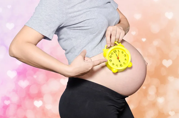 Pregnant woman's belly with clock — Stock Photo, Image