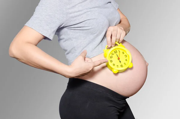 Pregnant woman's belly with clock — Stock Photo, Image