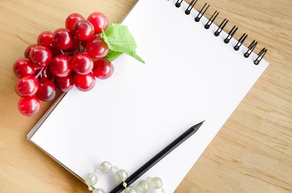 Enfocar la uva roja y el diario blanco en blanco sobre fondo de madera . — Foto de Stock