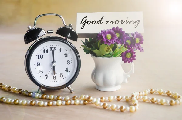 Alarm clock and Good morning tag with violet flower. — Stock Photo, Image
