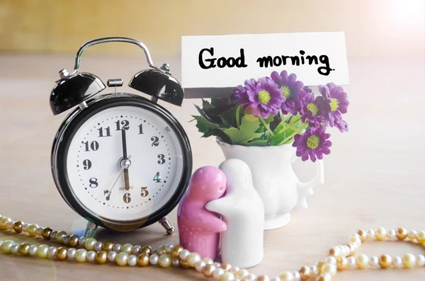 Flowers in a ceramic pots with purple vintage alarm clock. — Stock Photo, Image