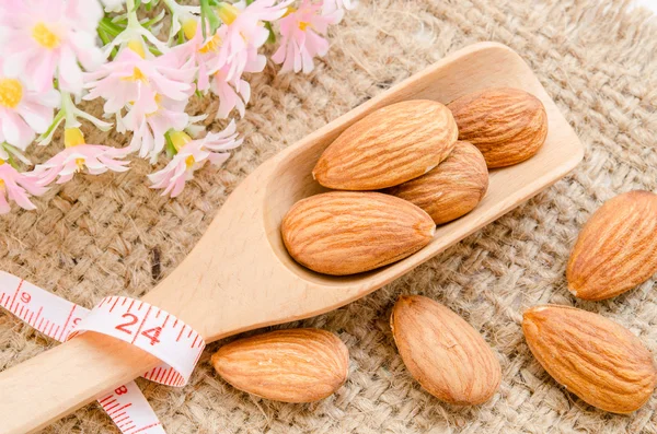 Amandes dans une cuillère en bois avec ruban à mesurer — Photo