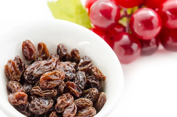 Dried raisins in white cup and fresh red grapes. — Stock Photo, Image