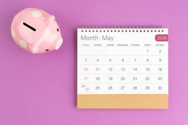 Mayıs 2026 Masa Takvimi ve mor arka planda pembe kumbara.