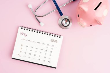 Mayıs 2026 masa takvimi ve pembe kumbaralı steteskop, sağlık konseptleri için tasarruf.