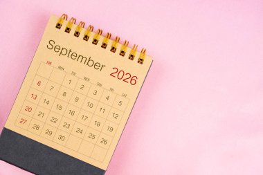 Pembe arkaplan üzerine Eylül 2026 için kahverengi masa takvimi.