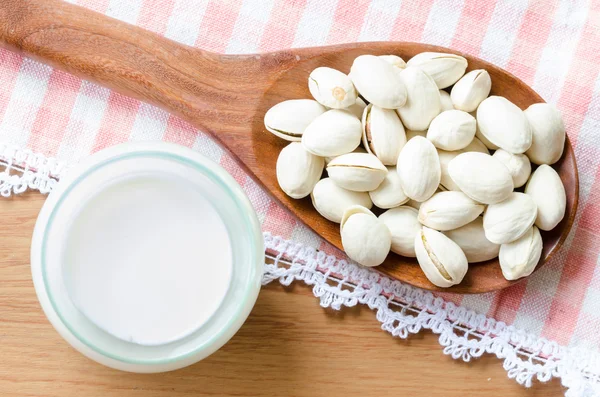 Pistacho en cuchara de madera con leche . —  Fotos de Stock