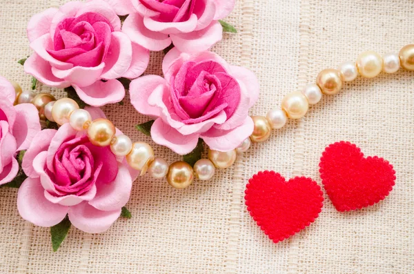 Κόκκινη καρδιά και ροζ τριαντάφυλλο σε ύφασμα φόντο. — Φωτογραφία Αρχείου