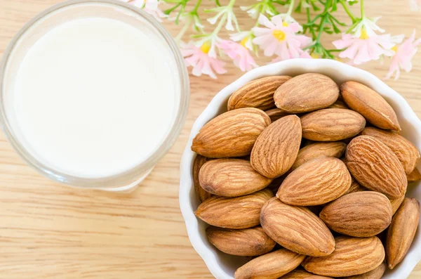 Almond in white cup and milk in glass. — Stock Photo, Image