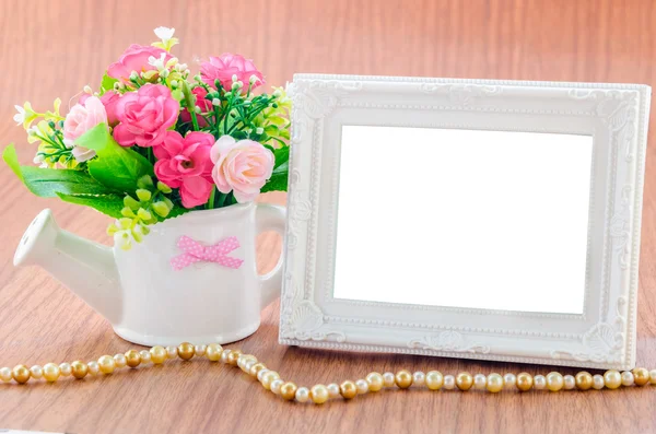 Flowers vase and vintage white picture frame on wooden desktop. — Stock Photo, Image