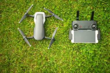 Helikopter ve uzaktan kumanda. Parktaki yeşil çimlerin üzerinde telefon var.