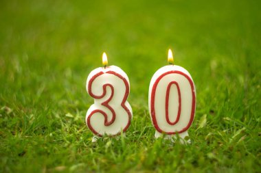 Doğum günü için yeşil arka planda 30 numara şeklinde mumlar yaktı.