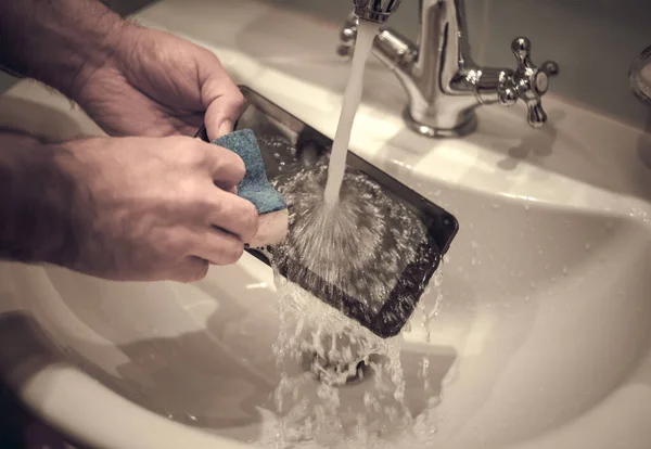Washing the tablet under running water in the sink, with a dish washing sponge. Disinfection of the tablet.