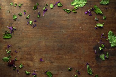 Çiçeklerin yeşil yapraklarıyla çevrili ahşap bir antika masa..