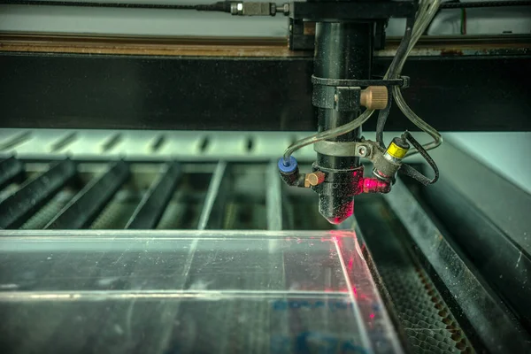 Üretim lazer makinesinin şeffaf plastiğinin kesilmesi. Kırmızı lazer ışını ve polyester.
